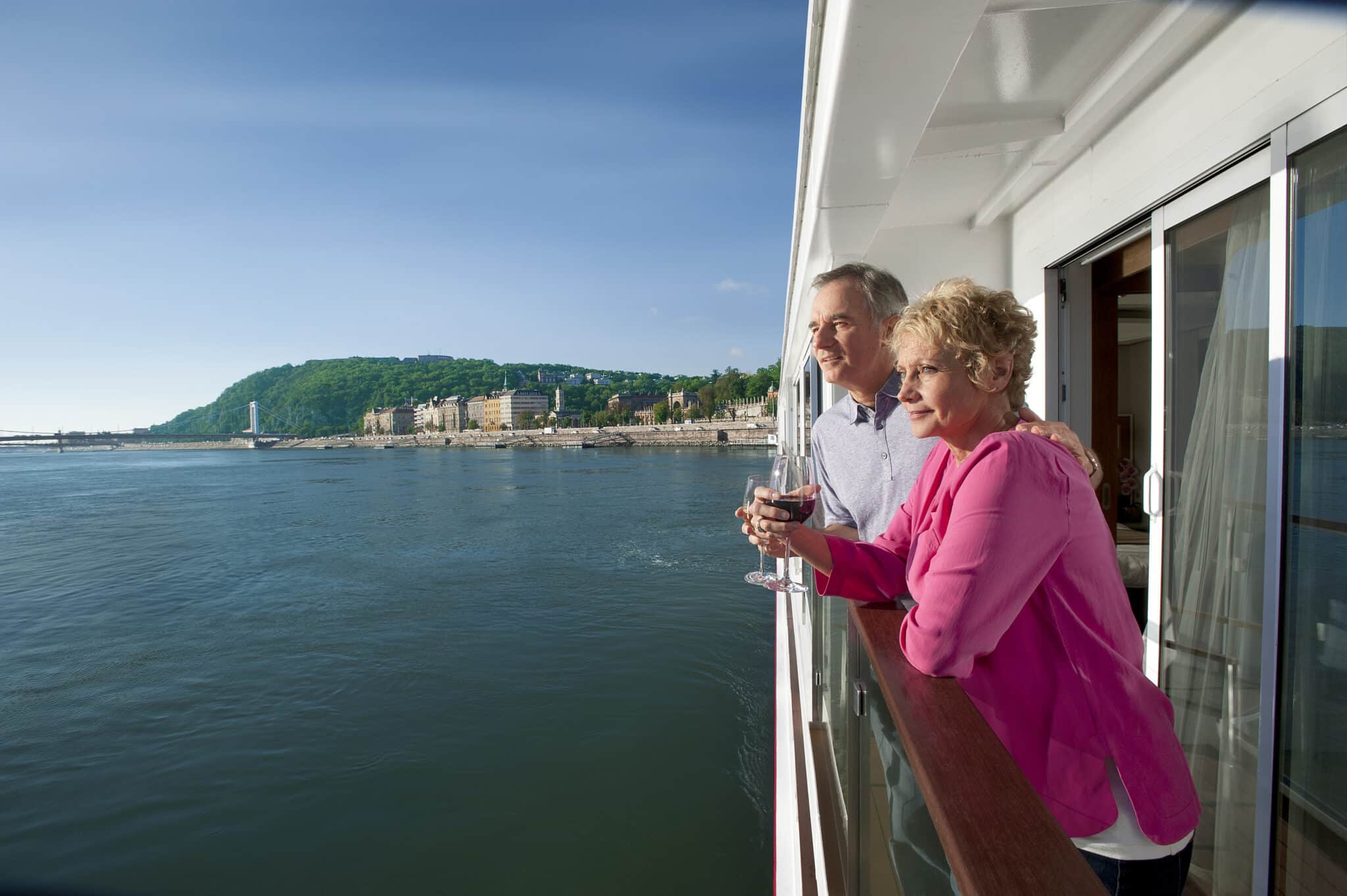Couple enjoying wine on a river cruise ship veranda overlooking European scenery